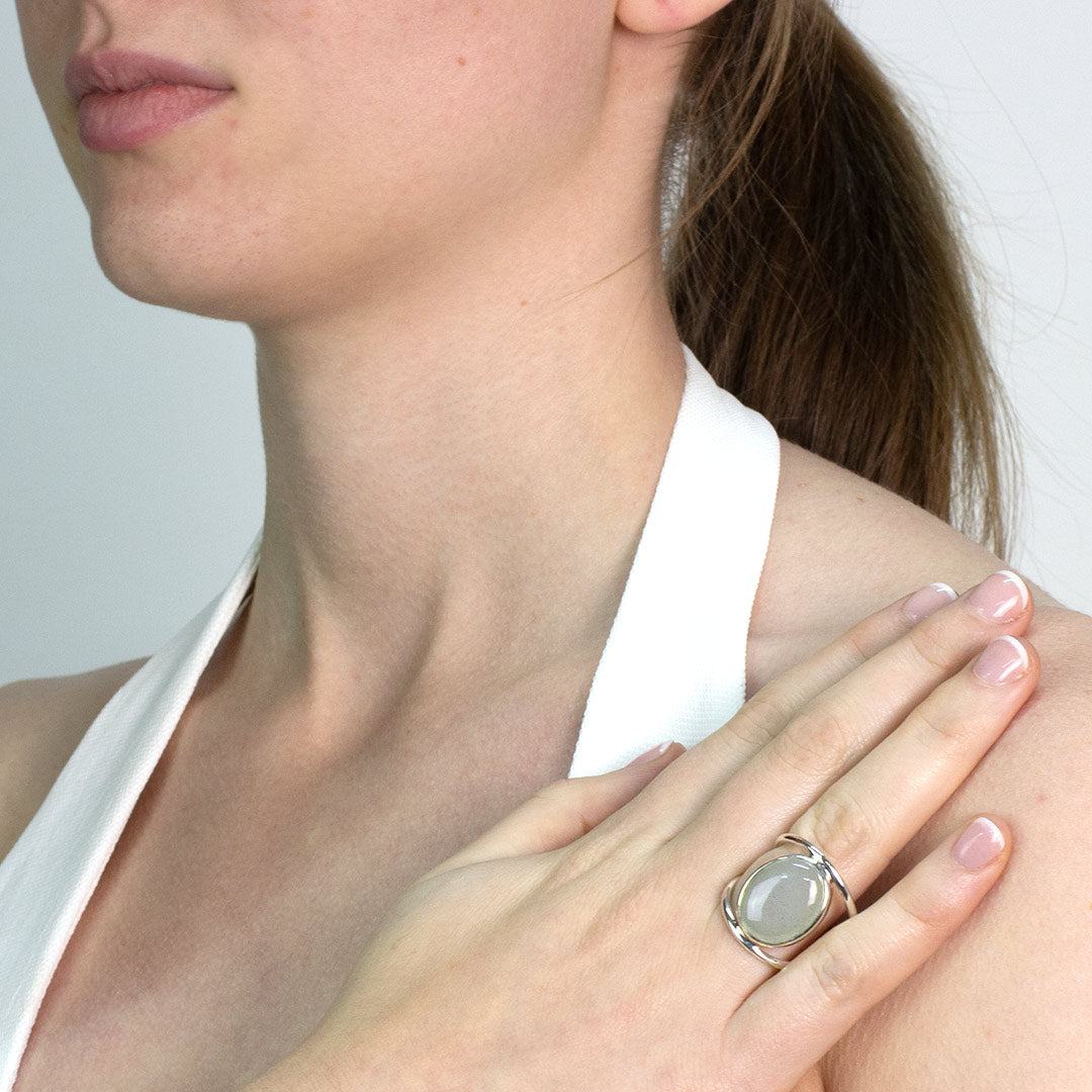 Woman wearing a silver ring with a light blue gemstone on a plain background