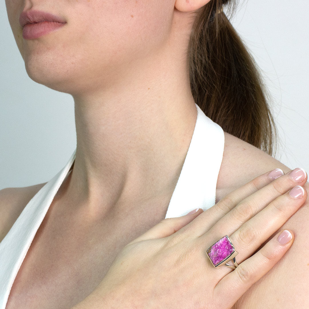 Woman wearing a silver ring with a rough pink gemstone on a white background