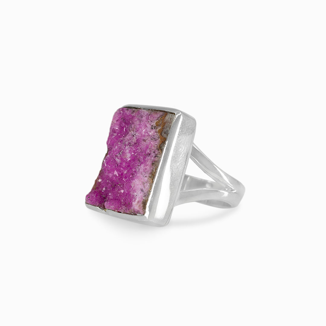 Silver ring with a rough pink gemstone on a white background