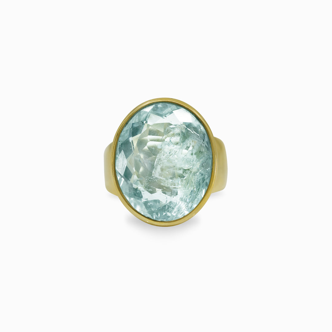 Golden ring with a light blue gemstone on a white background.