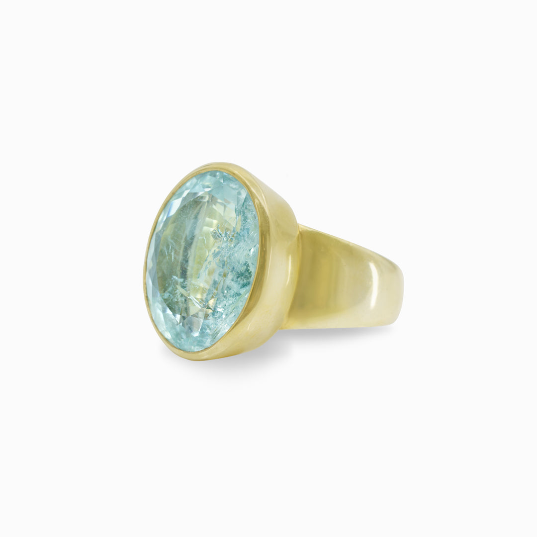 Golden ring with a light blue gemstone on a white background.