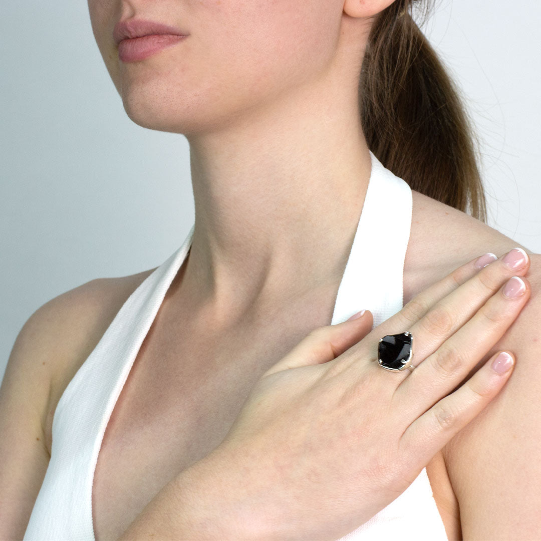 Woman wearing a silver ring with a black stone on a plain background.