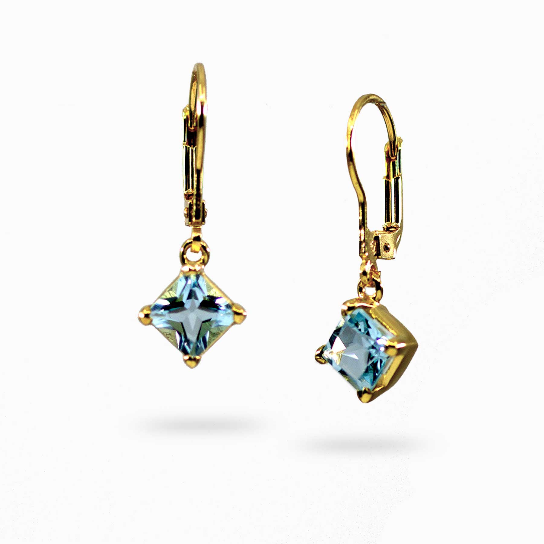 Golden earrings with blue gemstones on a white background
