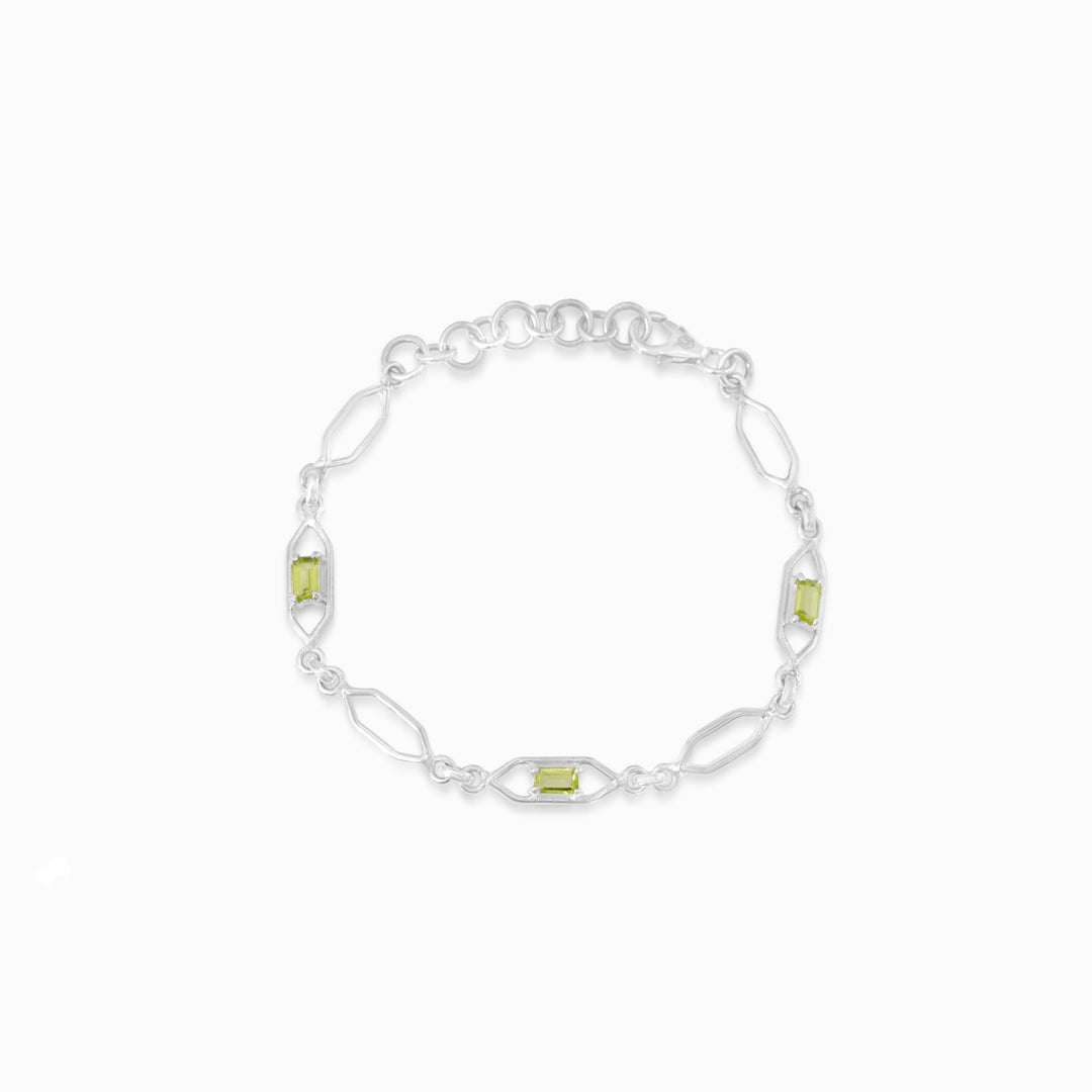 Silver bracelet with green gemstones on a white background