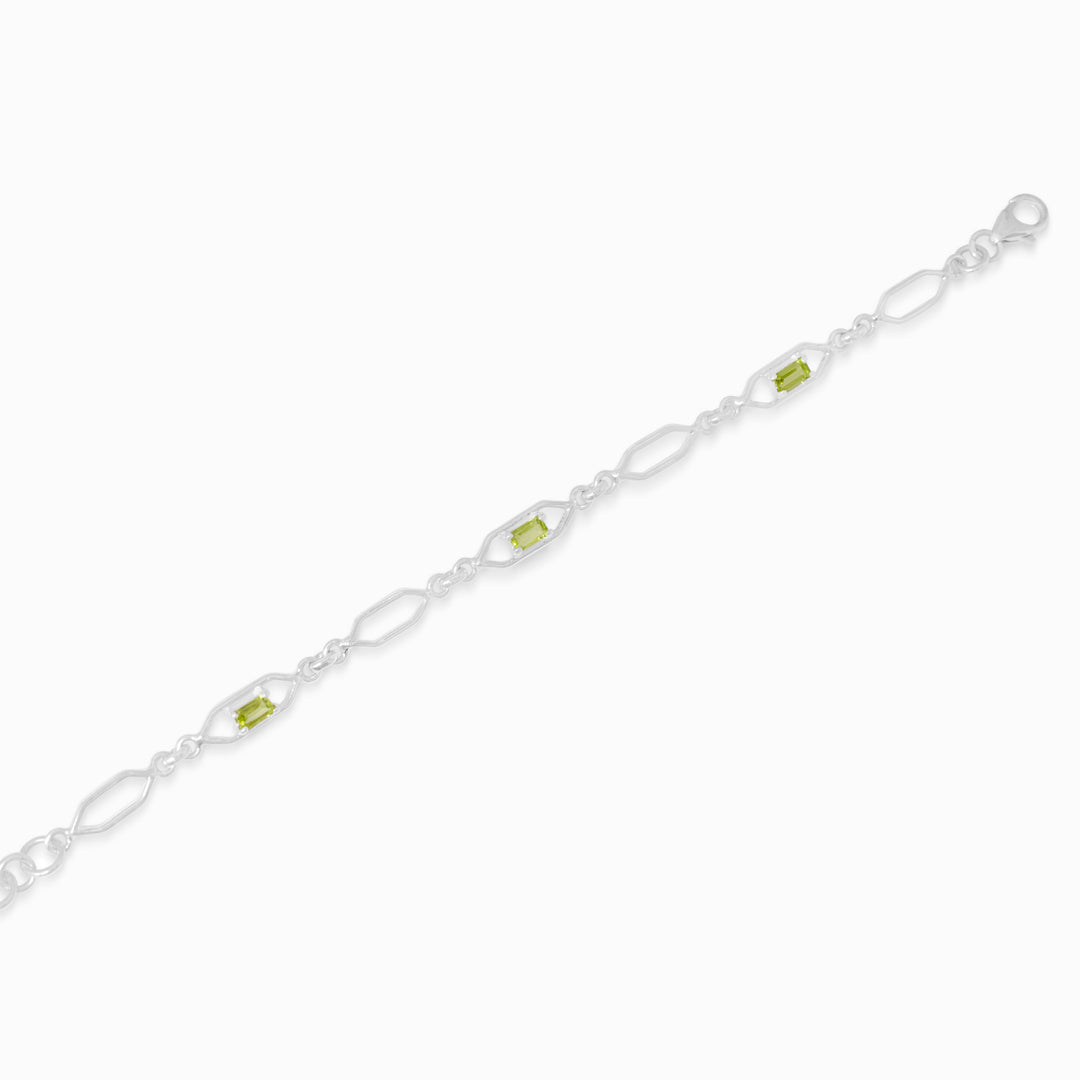 Silver bracelet with green gemstones on a white background