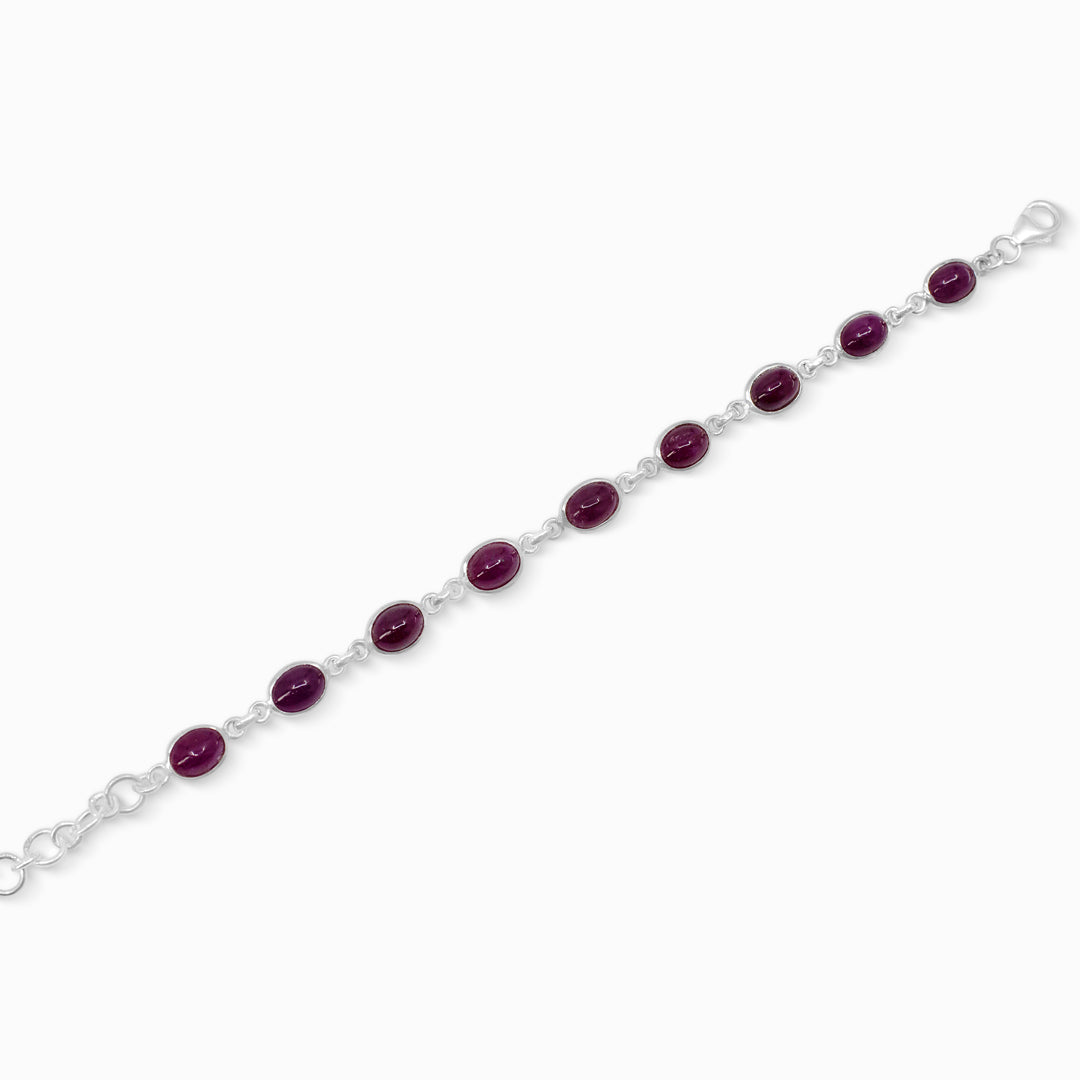 Silver bracelet with dark pink gemstones on a white background