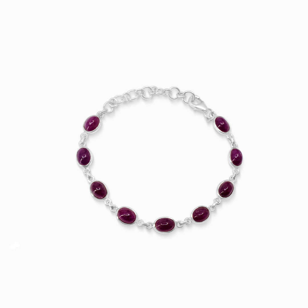 Silver bracelet with dark pink gemstones on a white background