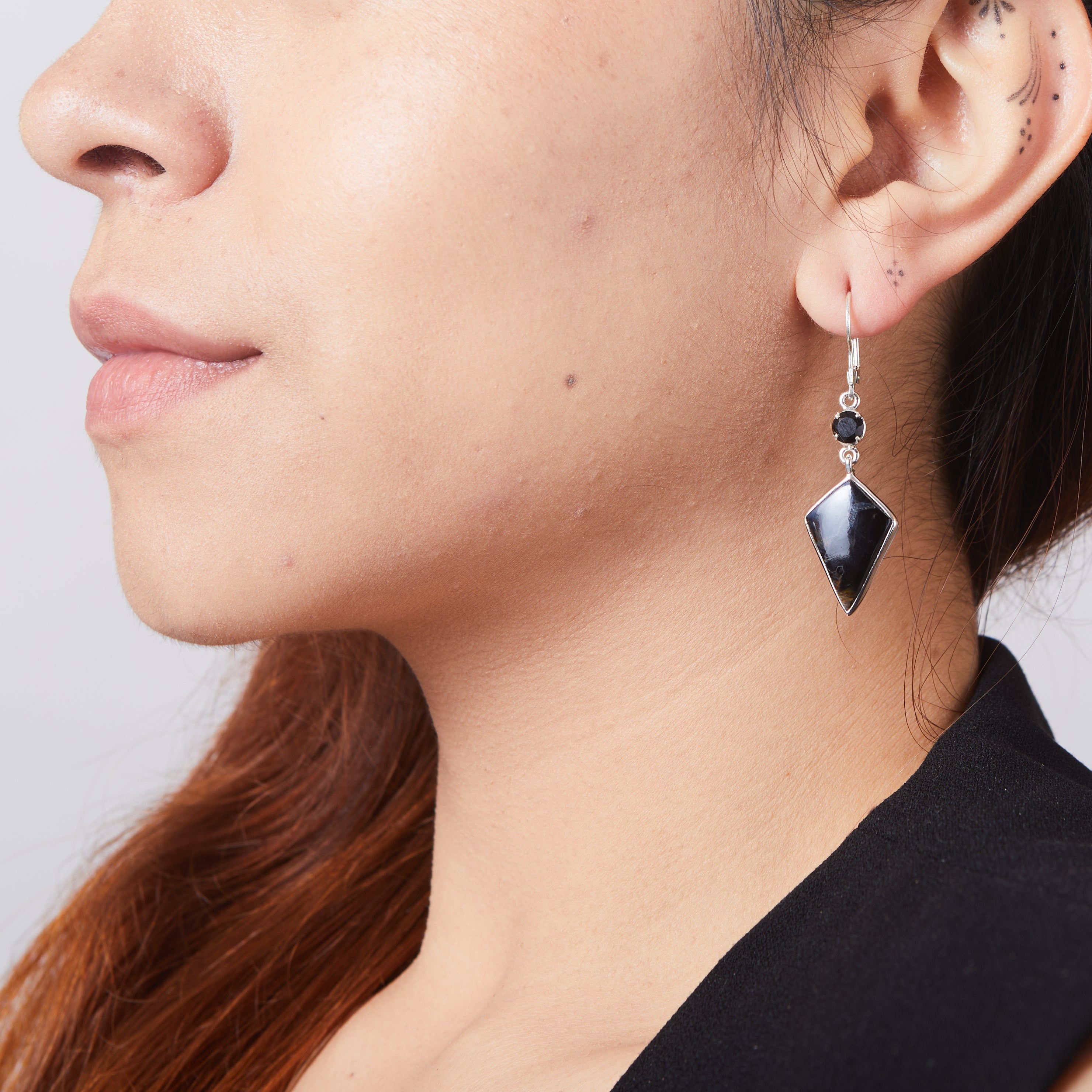 Pietersite and black onyx drop kite earrings with claw and bezel setting and clasp hooks on model