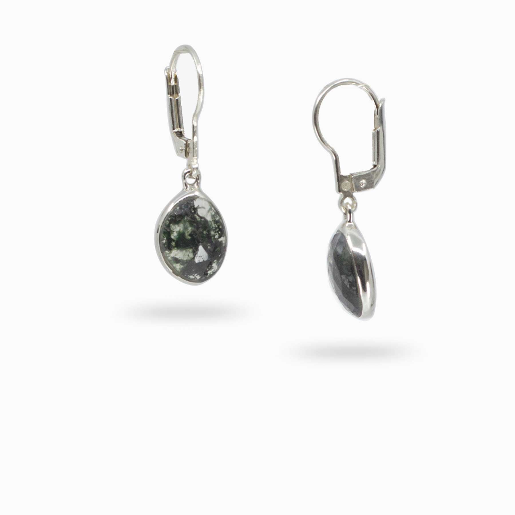 Pair of silver drop earrings with translucent stones with dark green inclusions on a white background
