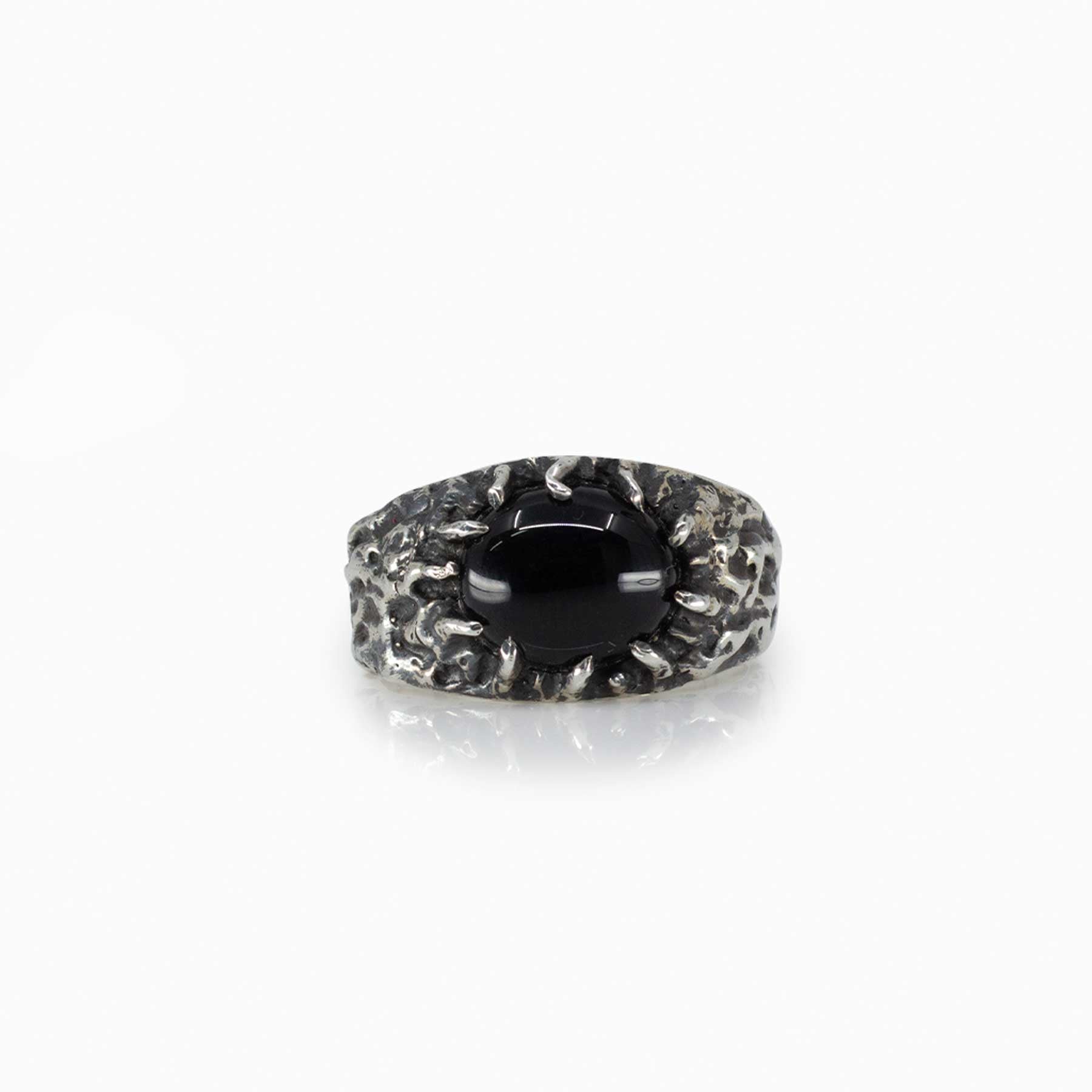 Silver ring with a black gemstone and textured band on a white background