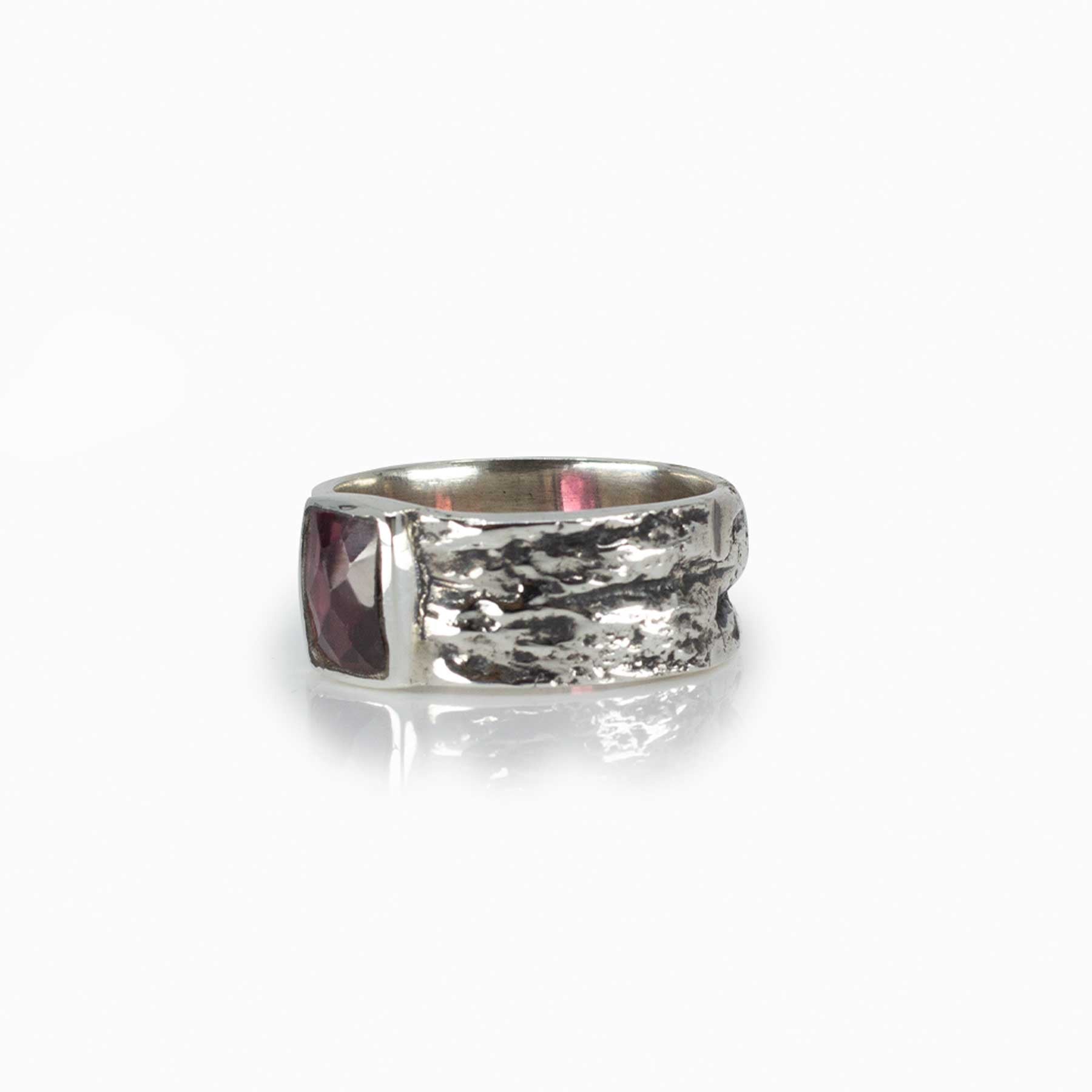 Silver ring with a red gemstone on a white background