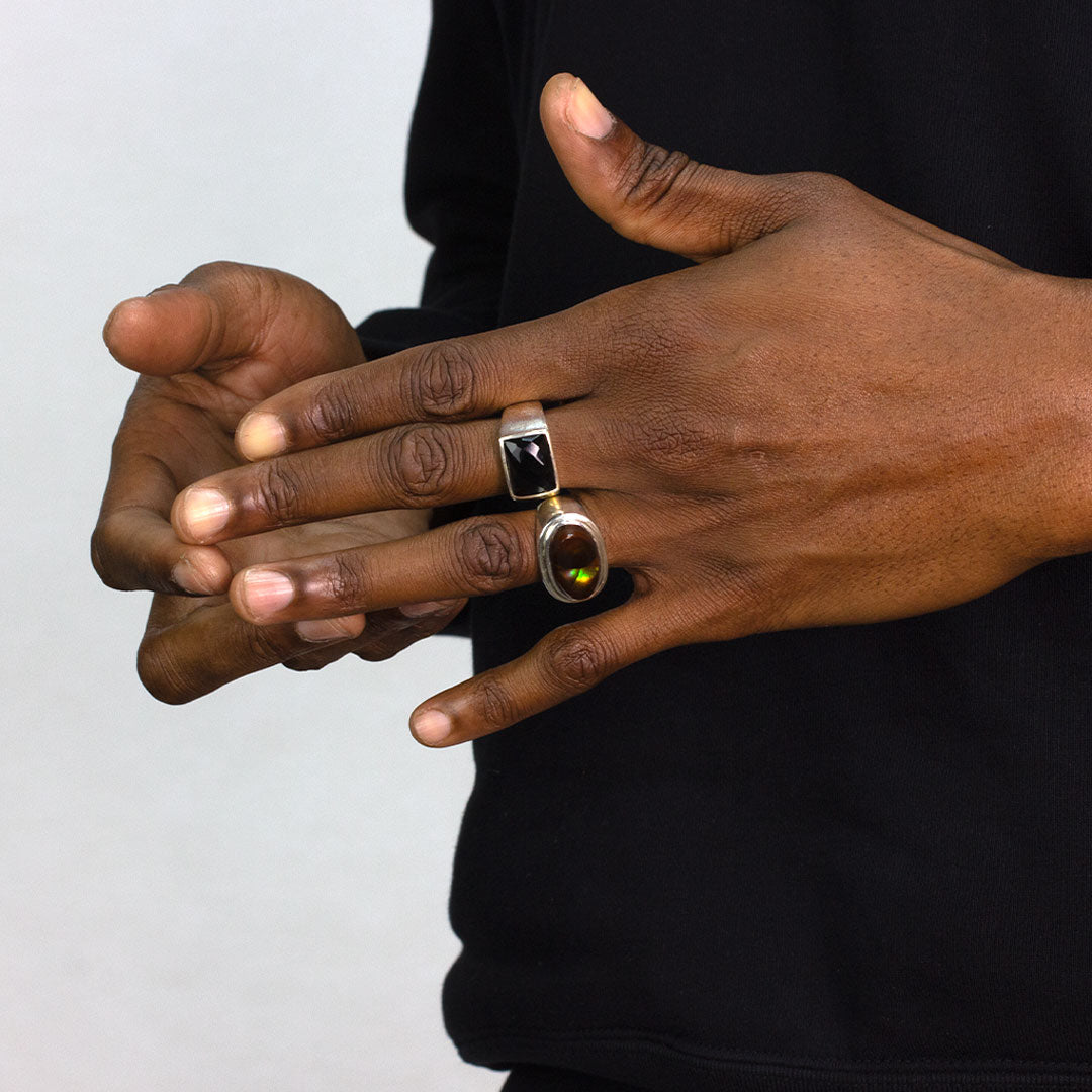 Close-up of a person wearing a silver ring with a black gemstone on a white background