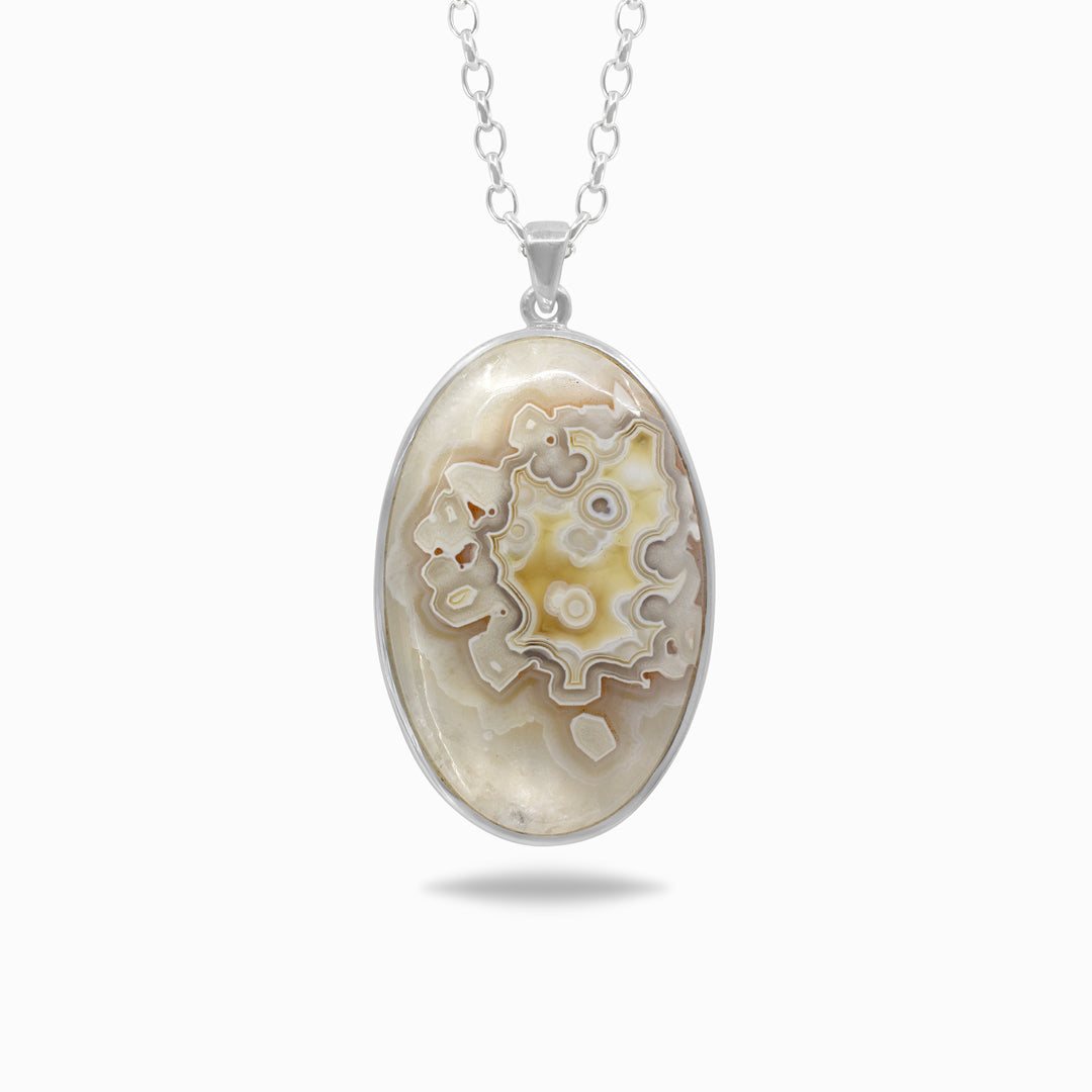 Oval-shaped pendant with patterned stone on a white background