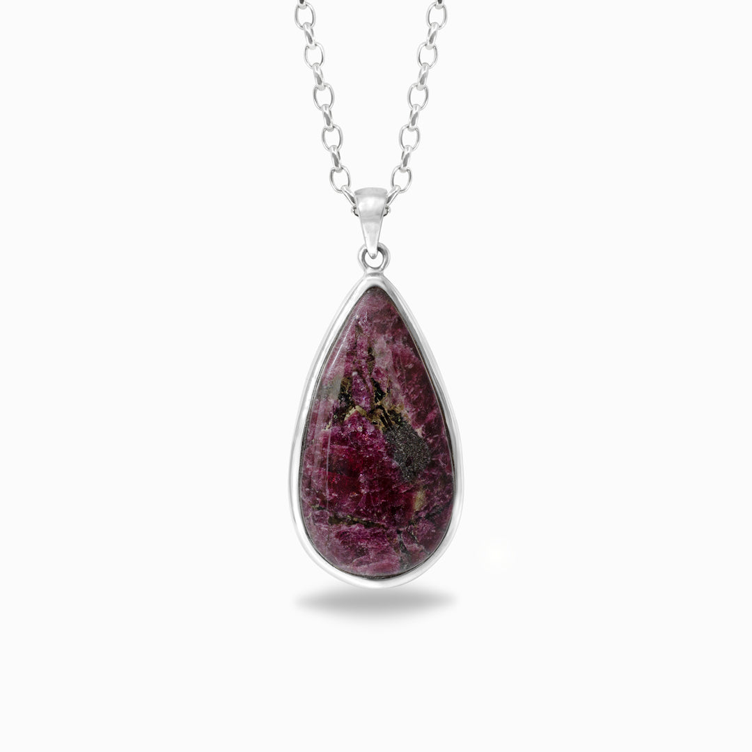 Teardrop-shaped pinky-red crystal pendant on a silver chain against a white background