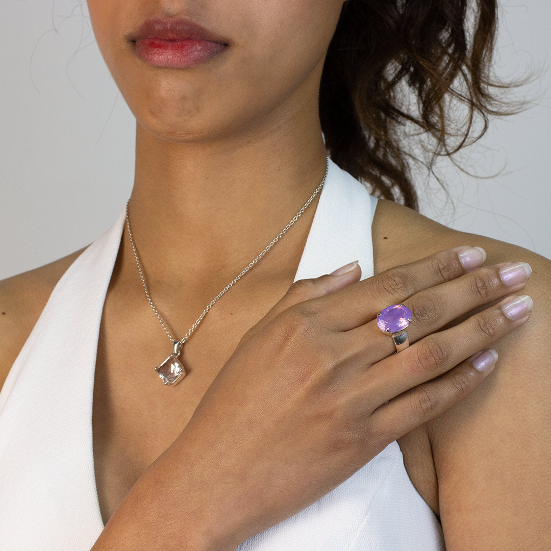 Woman wearing a silver ring with a purple gemstone on a plain background