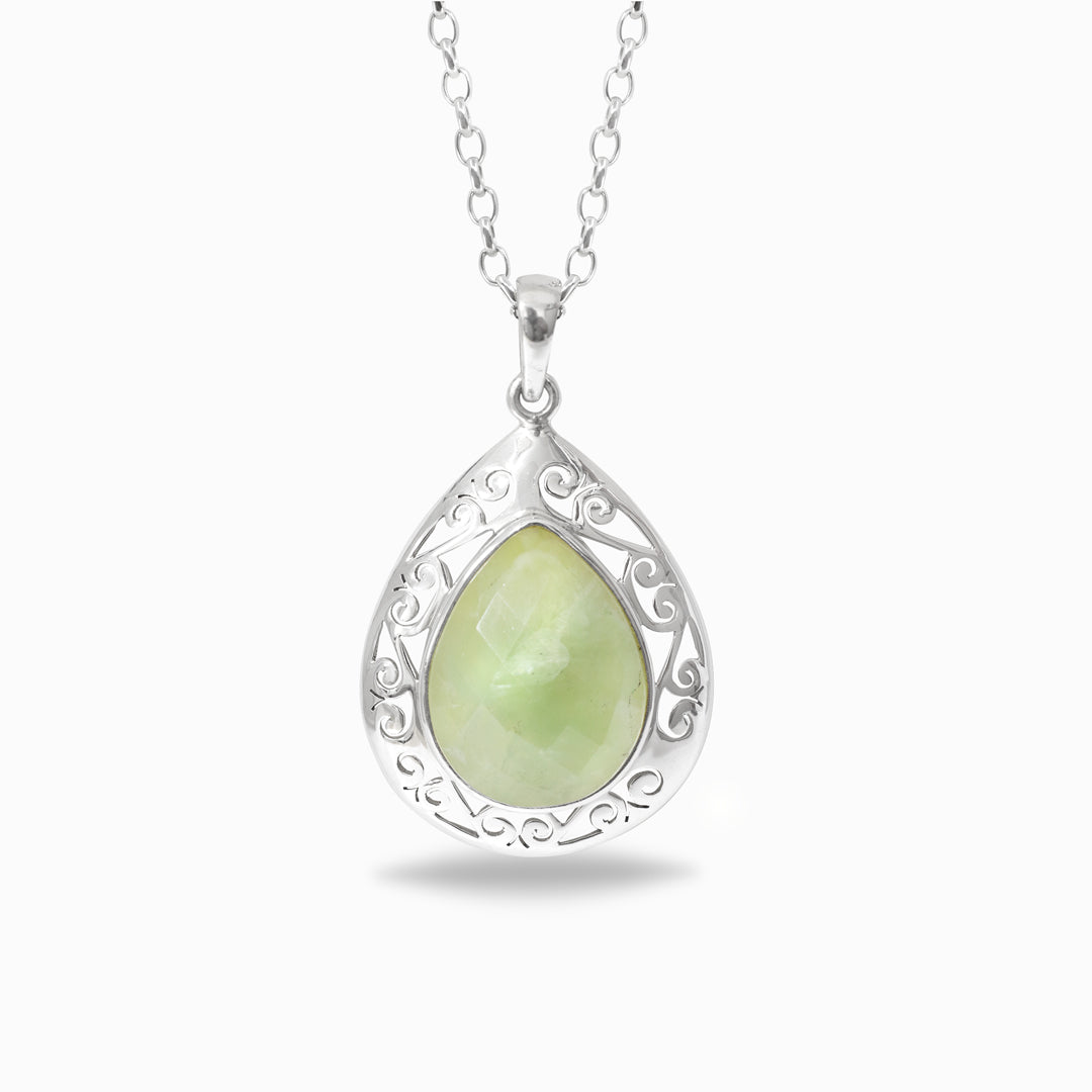 Teardrop-shaped pendant with green gemstone and silver frame on a white background