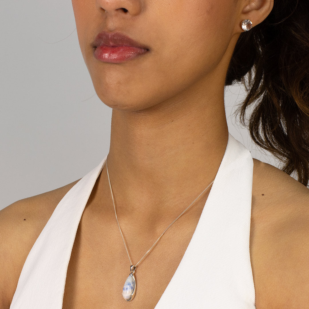 Woman wearing a teardrop-shaped pendant with blue and white against a plain background