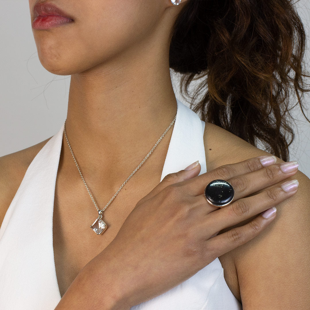 Woman wearing a ring with a round black stone on a plain background