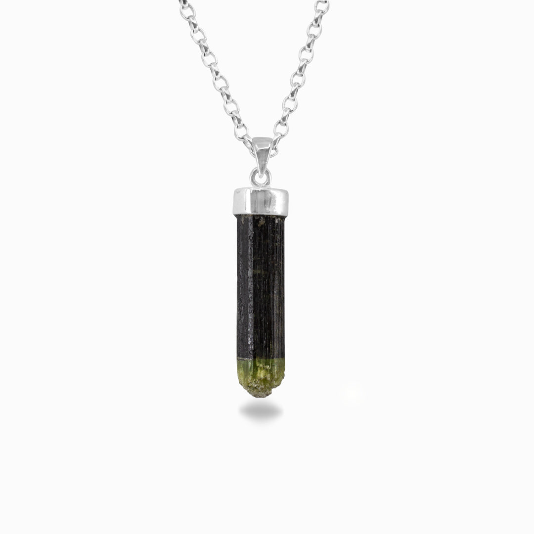 Silver necklace with a green crystal pendant on a white background