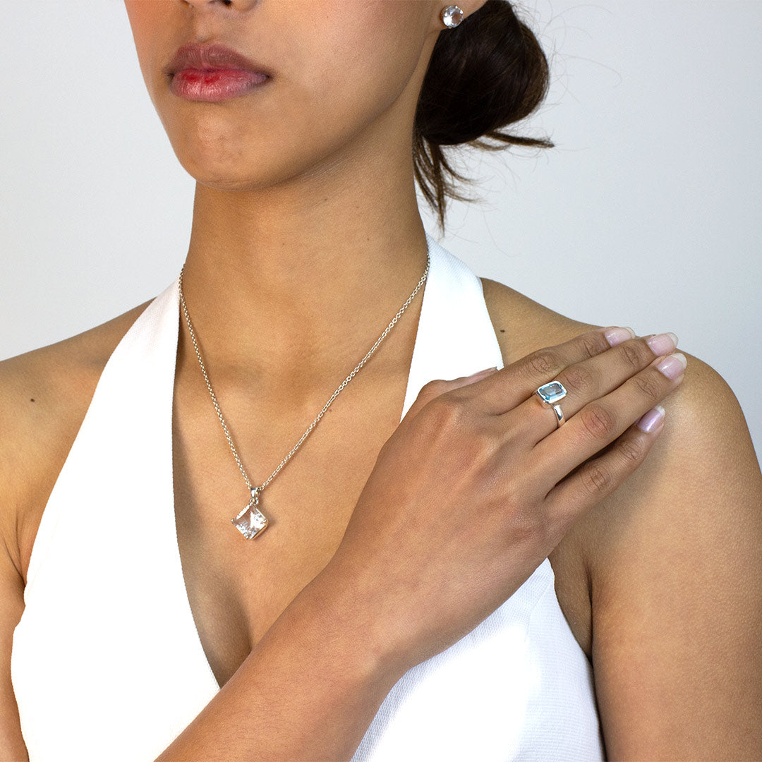 Woman wearing a silver ring with a rectangular blue gemstone on a plain background