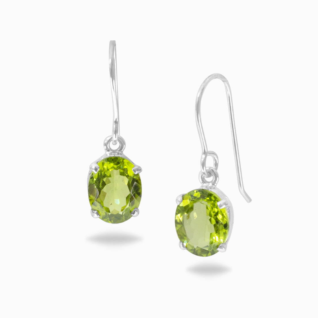 Pair of silver drop earrings with green gemstones on a white background