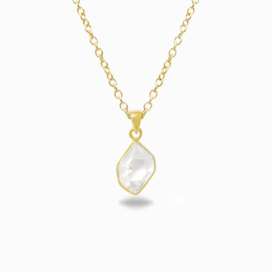 Gold necklace with a clear pendant on a white background