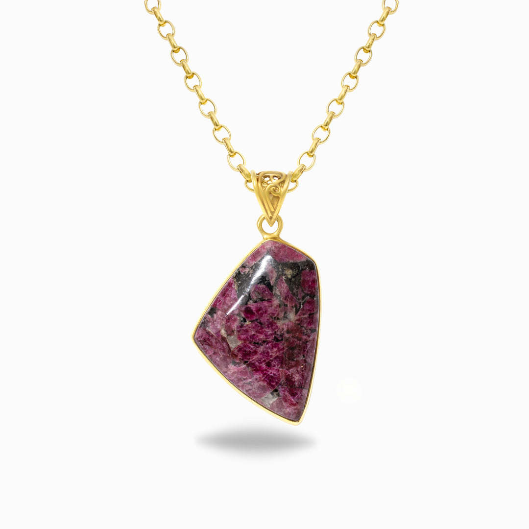 Gold necklace with a pink stone pendant on a white background