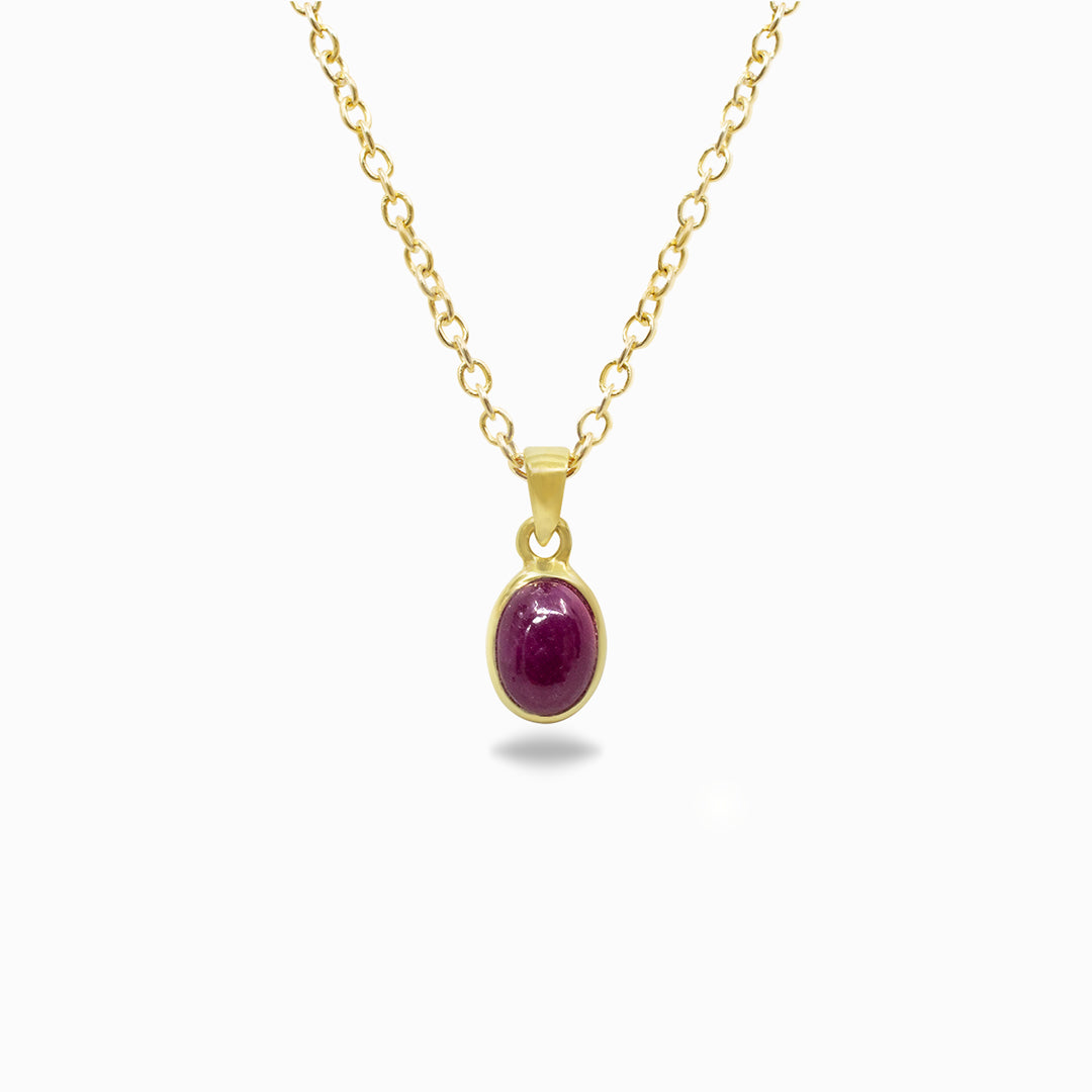 Gold necklace with a dark pink gemstone pendant on a white background