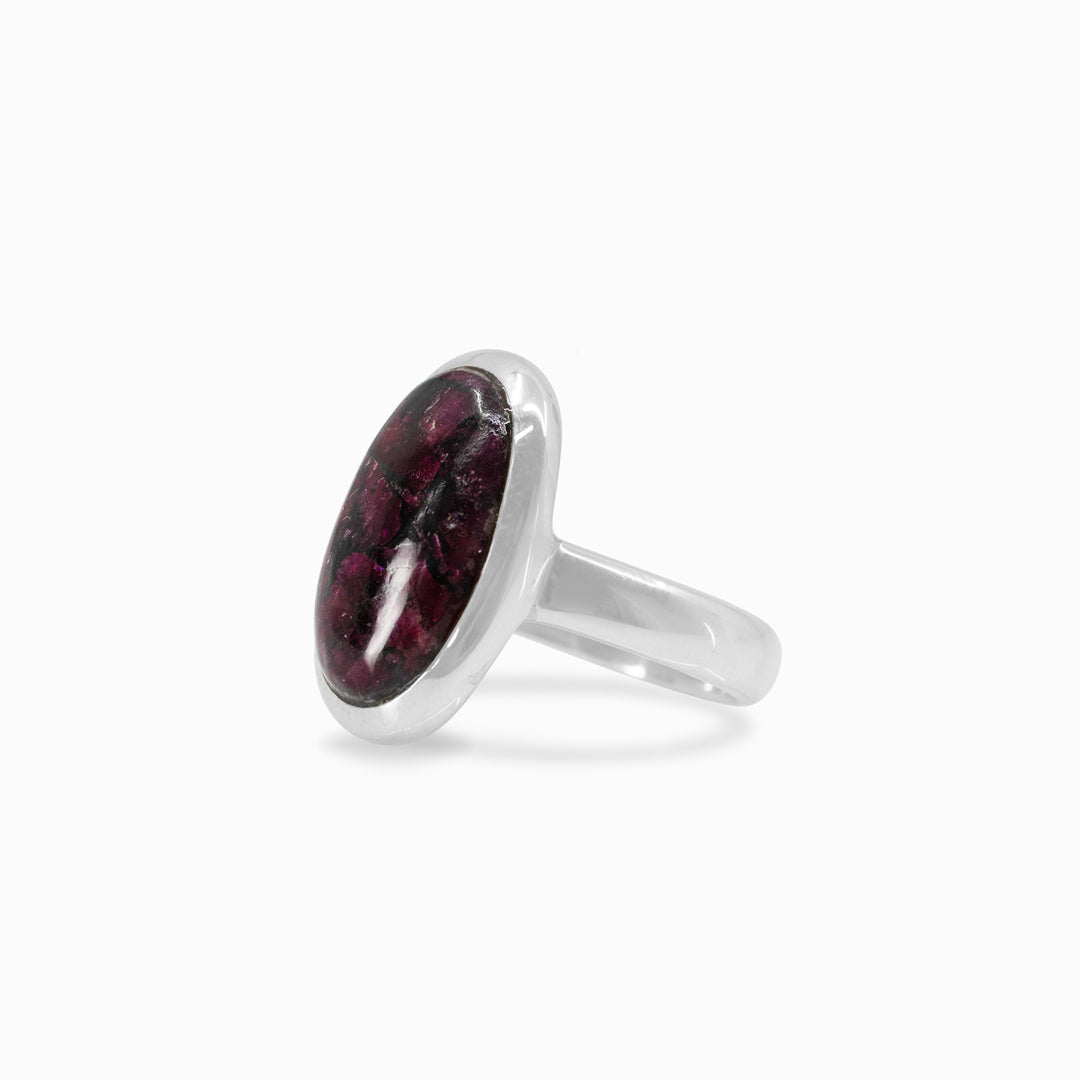 Silver ring with a dark pink gemstone on a white background