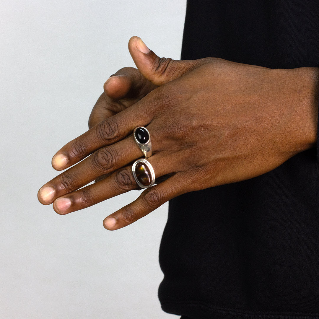 Hand wearing two rings on a plain background