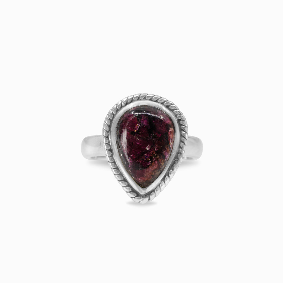 Silver ring with a dark pink gemstone on a white background