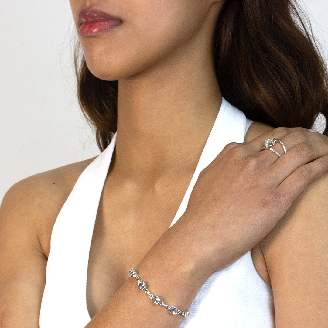 Woman wearing a silver bracelet with blue gemstones on a plain background