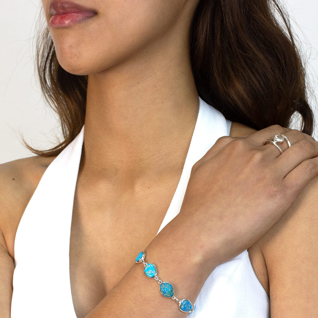 Woman wearing a Turquoise stone bracelet on a plain background