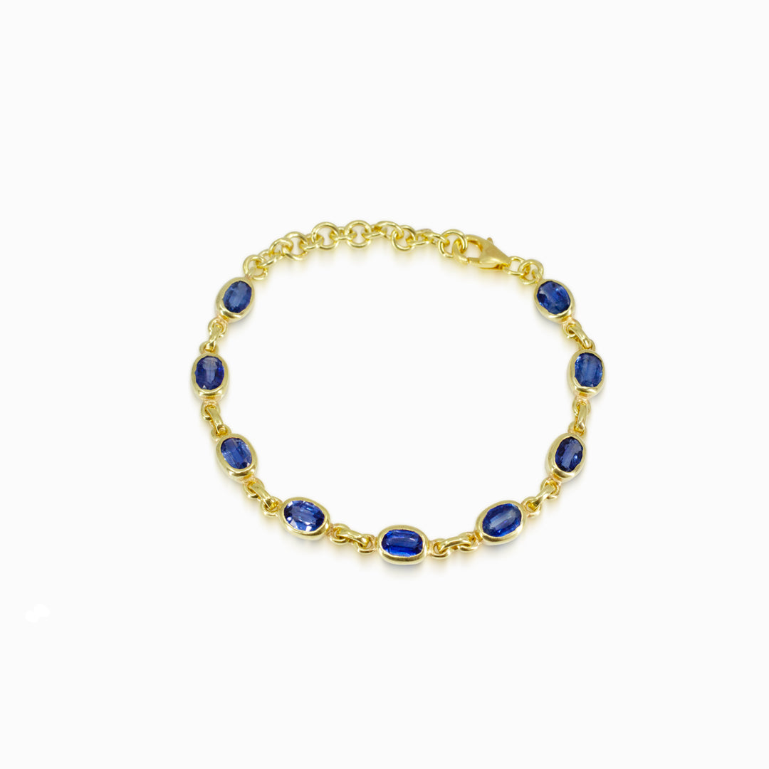 Gold bracelet with blue stones on a white background