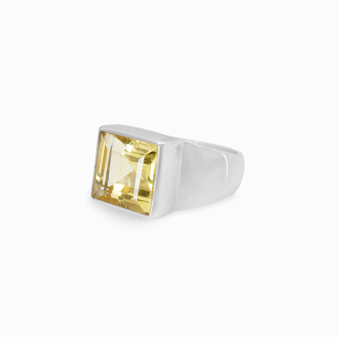 Silver ring with a yellow gemstone on a white background
