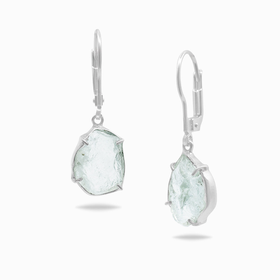 Pair of silver earrings with light blue gemstones on a white background