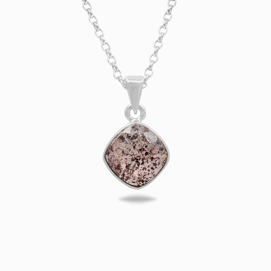 Silver necklace with a pendant featuring a clear stone with red and pink inclusions on a white background