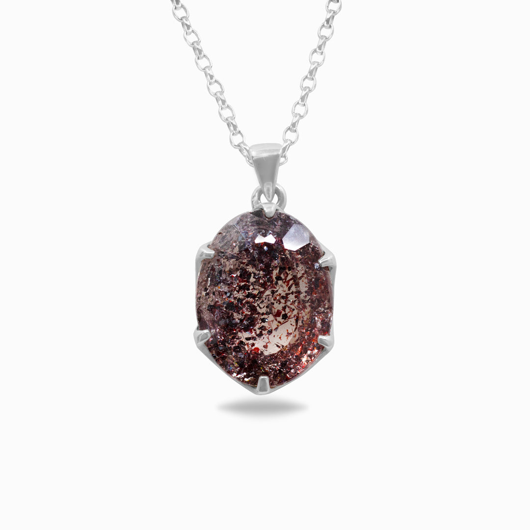 Silver necklace with a pendant featuring a clear gemstone with red and pink inclusions on a white background