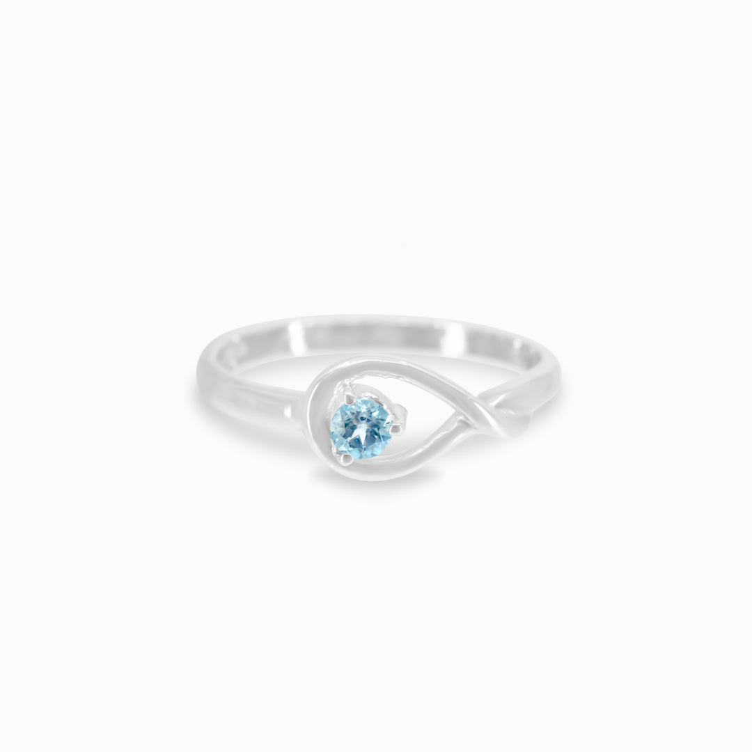 A silver ring featuring a blue gemstone in the centre, set against a white background.