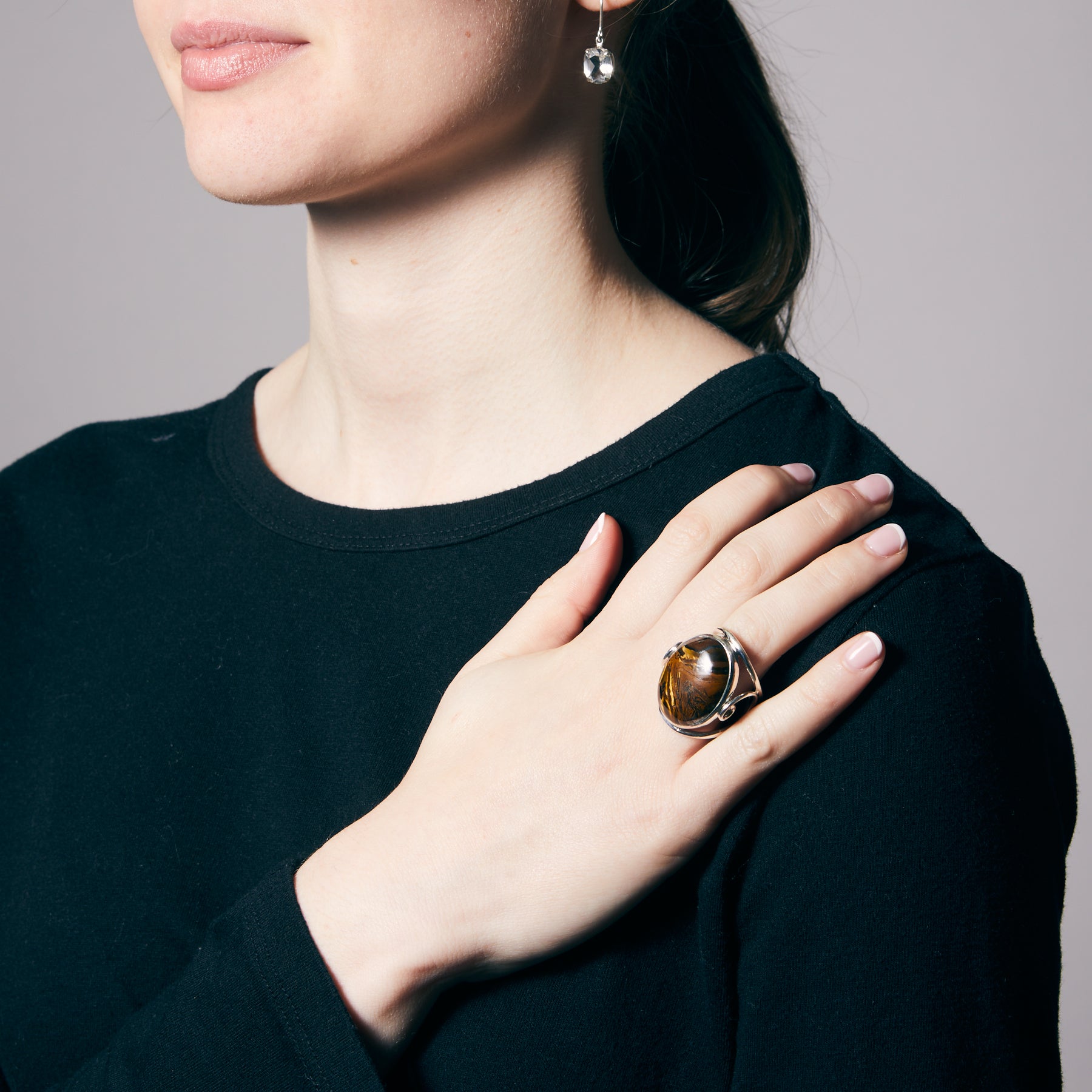 Person wearing a black shirt with a Tiger Iron ring on a neutral background