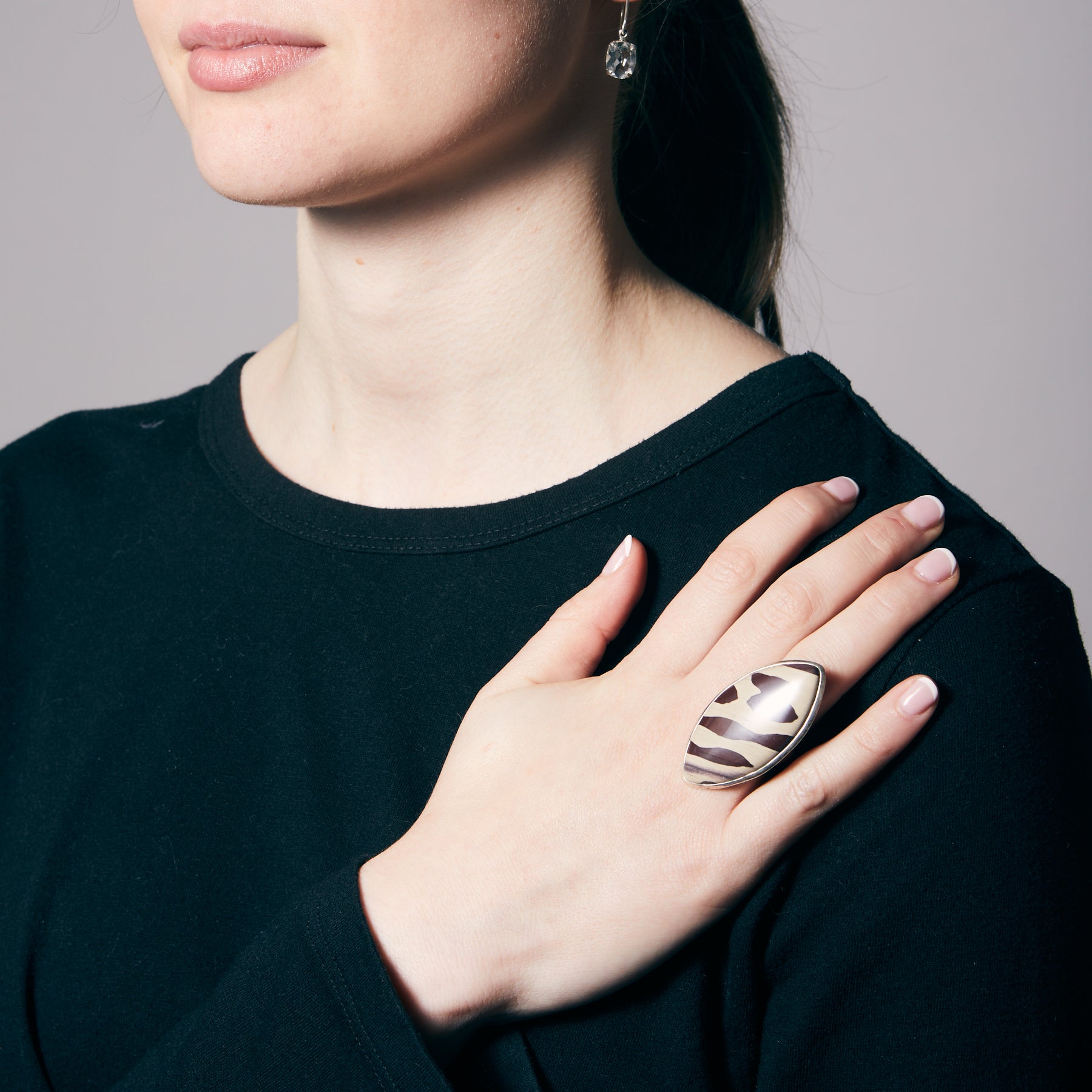 Person wearing a silver ring with zebra pattern on a plain background.
