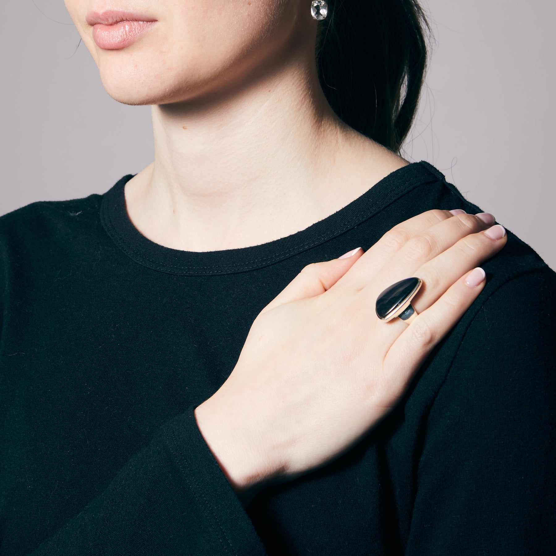 Person wearing a silver ring with a dark blue gemstone on a white background