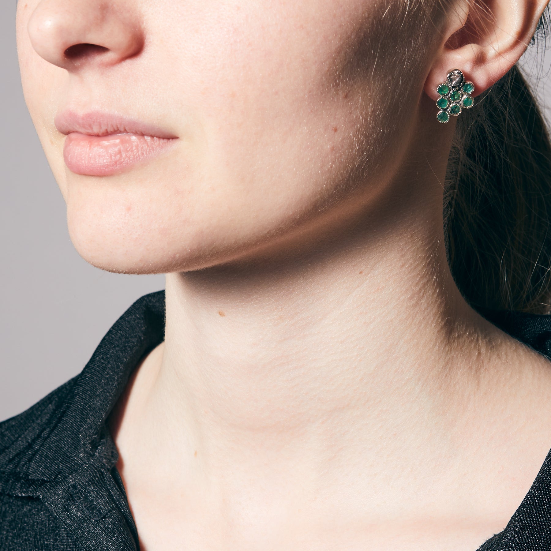 Close-up of a person wearing a grape shaped earring on a neutral background