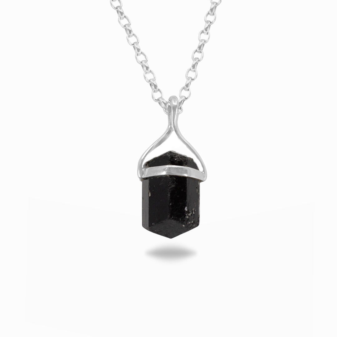 Silver necklace with a black raw gemstone on a white background