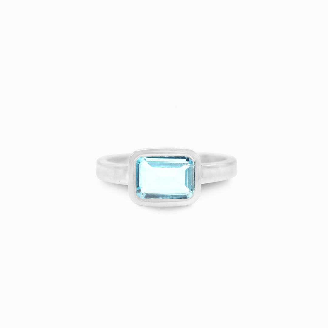 Silver ring with a rectangular blue gemstone on a white background