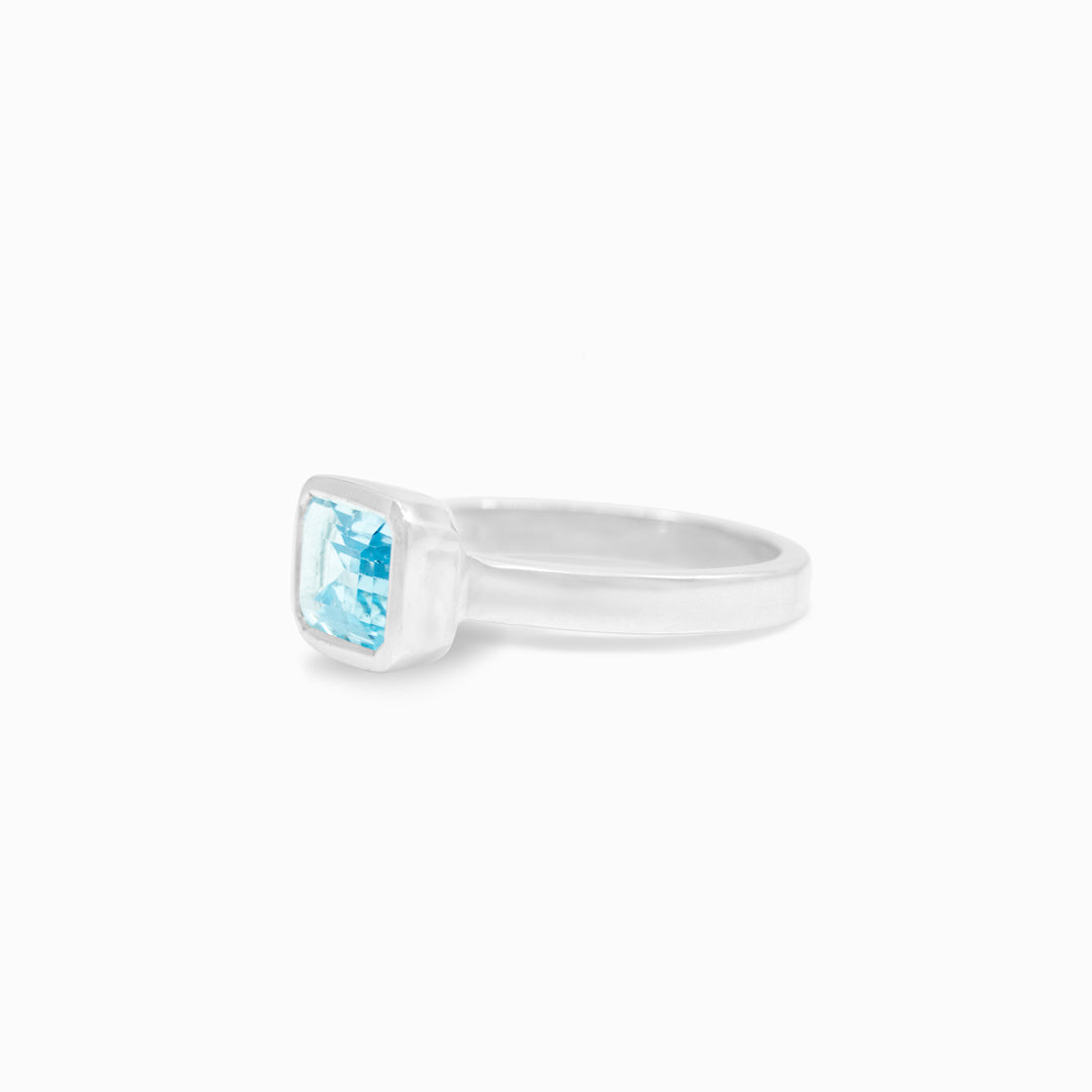 Silver ring with a rectangular blue gemstone on a white background