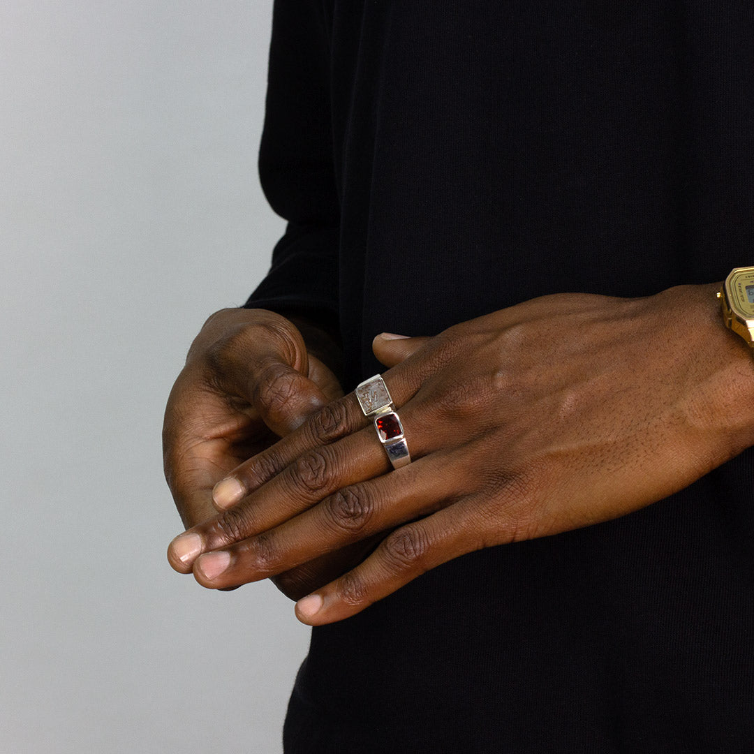 Hand with multiple silver rings on a plain background