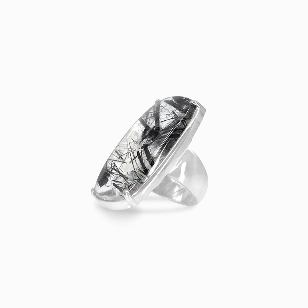 Silver ring with a black and clear patterned stone on a white background
