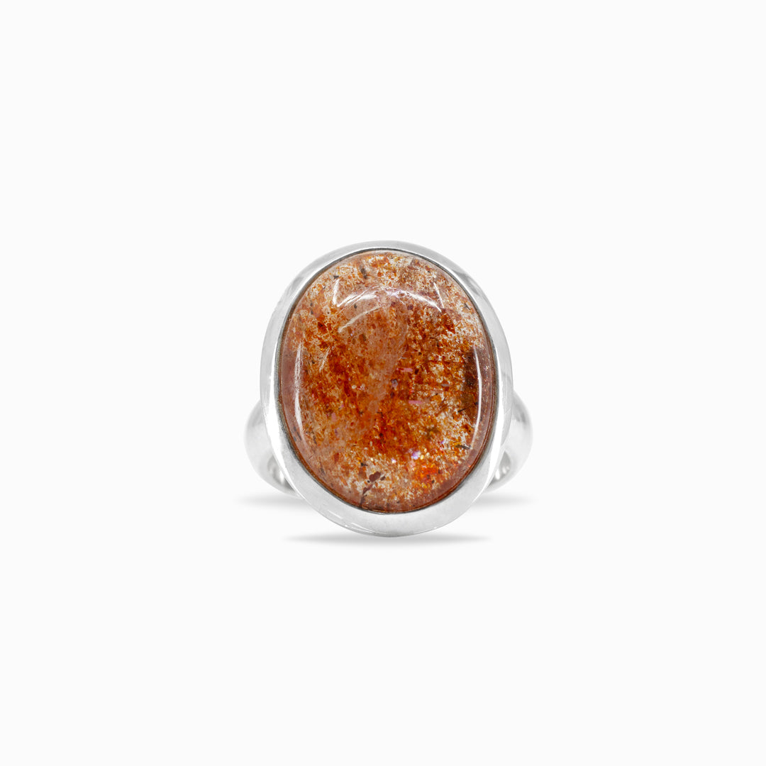 Silver ring with an oval orange gemstone on a white background