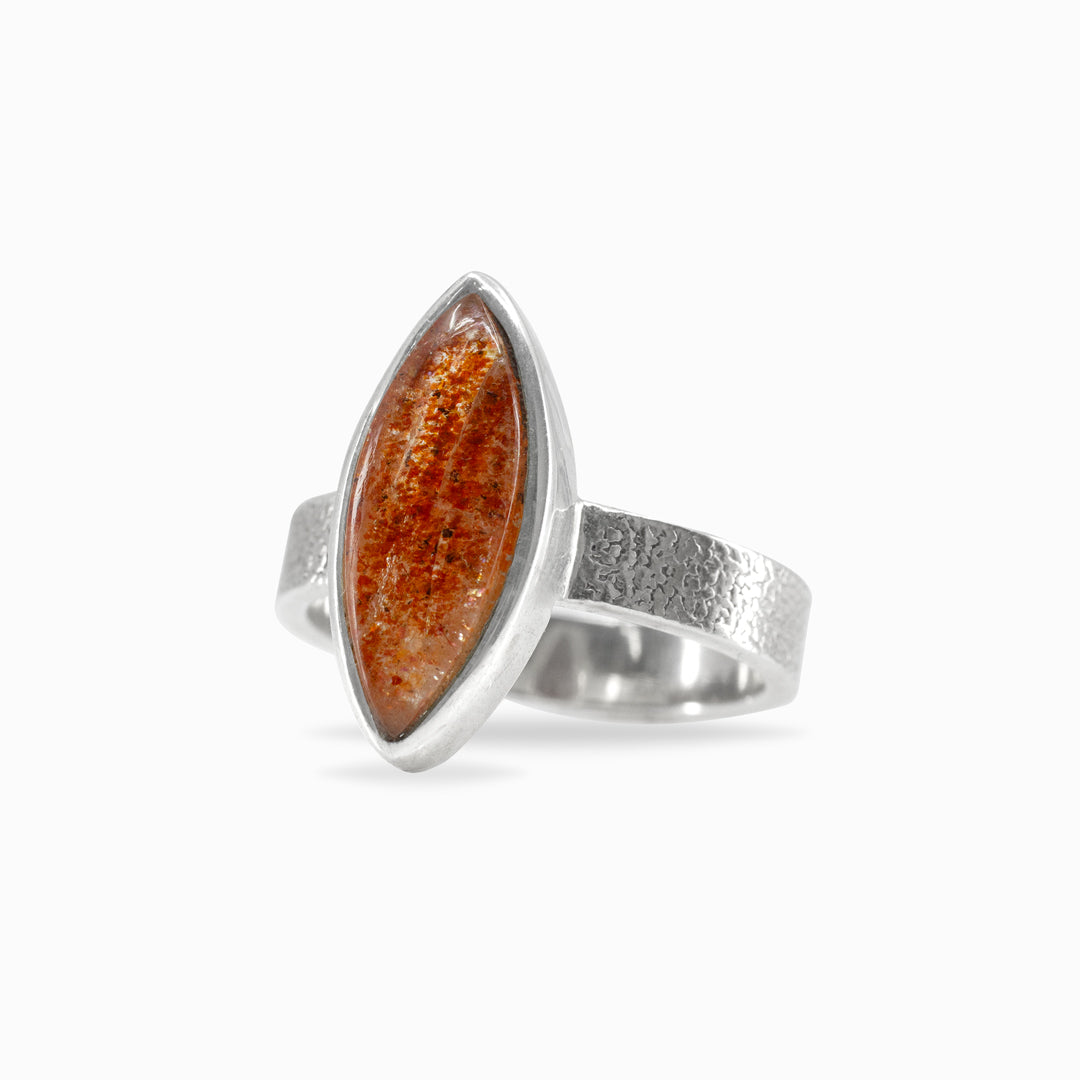 Silver ring with a marquise-shaped orange gemstone on a white background